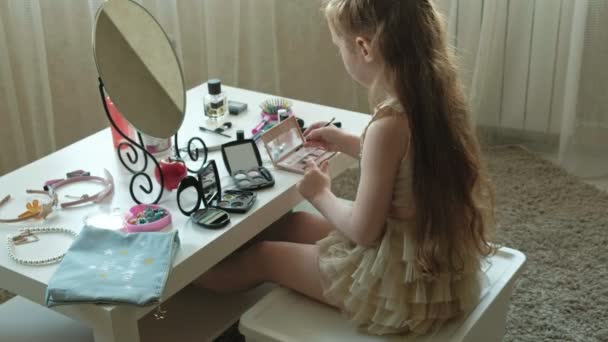 Маленька дівчинка з рудим волоссям кладе тіні на повіки, дивиться у дзеркало, макіяж, обличчя, моду, стиль, косметику — стокове відео