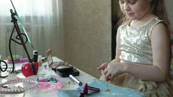 Petite fille aux cheveux roux met une bague à son doigt, essaie les accessoires, regarde dans le miroir, maquillage, visage, mode, style, cosmétiques — Video