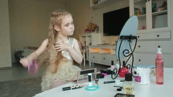 Маленькая девочка с рыжими волосами расчески, смотрит в зеркало, макияж, лицо, мода, стиль, косметика, уход за волосами — стоковое видео