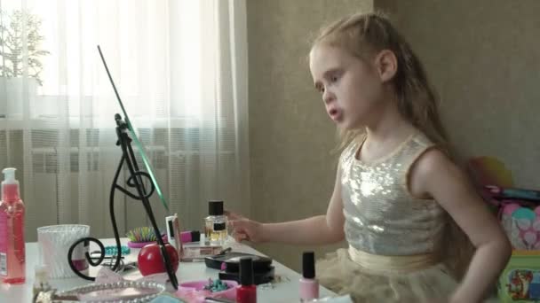Petite fille aux cheveux roux fait des visages dans le miroir, regarde dans le miroir, maquillage, visage, mode, style, cosmétiques — Video