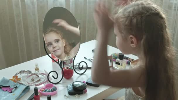 Liten flicka med rött hårkammar håret, ser ut i spegeln, makeup, ansikte, mode, stil, kosmetik, hårvård — Stockvideo