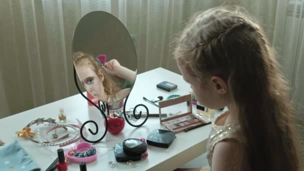A little girl with red hair fastens hairpins on hair, tries on accessories, looks in the mirror, makeup, face, fashion, style, cosmetics portrait — Stock Video