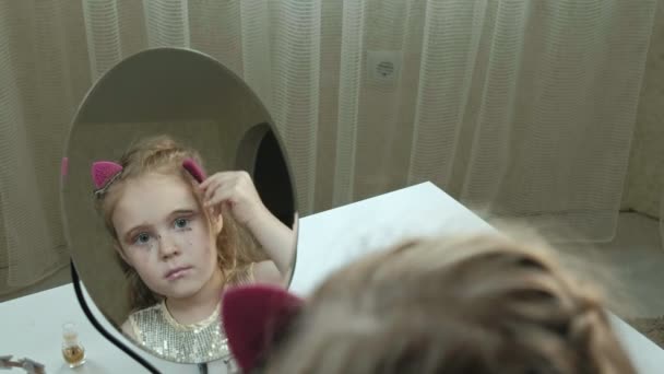 Une petite fille aux cheveux roux fixe les épingles à cheveux sur les cheveux, essaie les accessoires, regarde dans le miroir, maquillage, visage, mode, style, portrait cosmétique — Video