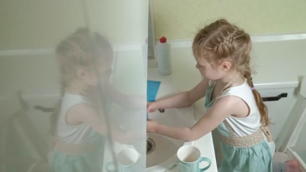 穿着围裙的漂亮小女孩站在椅子上 在明亮的厨房里洗碗 帮助父母4K — 图库视频影像