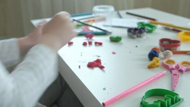 Una bambina gioca con la plastilina, si separa in piccoli pezzi, sul desktop sono figure e matite colorate, lo sviluppo di abilità motorie fini delle mani — Video Stock