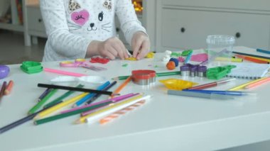 mutlu küçük kız hamuru ile oynuyor, bir rakam sculpts, masaüstünde rakamlar ve renkli kalemler, ellerin iyi motor becerilerinin geliştirilmesi