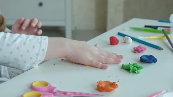 Heureuse petite fille joue avec la plasticine de couleur, rouleaux boules, les mains sur le bureau sont des chiffres et crayons de couleur, le développement de la motricité fine des mains — Video