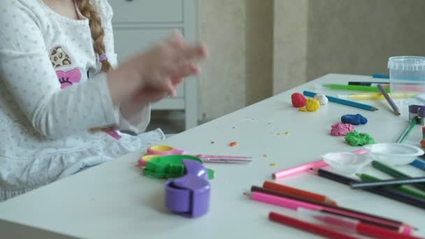 Heureuse petite fille joue avec la plasticine de couleur, rouleaux boules, les mains sur le bureau sont des chiffres et crayons de couleur, le développement de la motricité fine des mains — Video