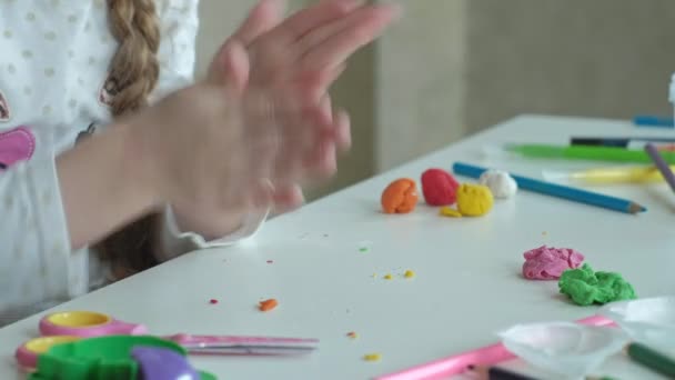 Menina feliz brinca com plasticina colorida, bolas de rolos, mãos na área de trabalho são figuras e lápis de cor, o desenvolvimento de habilidades motoras finas de mãos — Vídeo de Stock