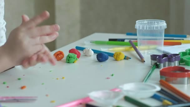 Feliz niña juega con plastilina de colores, rollos de bolas, las manos en el escritorio son figuras y lápices de colores, el desarrollo de habilidades motoras finas de las manos — Vídeos de Stock