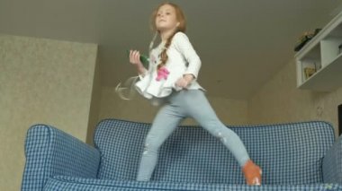 elleri ve atlama, odasında kanepede dans kulaklıklar bir telefon ile küçük kız