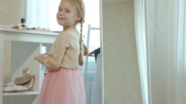 pigtails pembe bir etek ile neşeli küçük kız dudaklarına ruj ayna, ona anne gardırop önünde boyalar