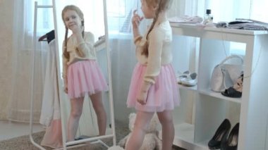 pigtails pembe bir etek ile neşeli küçük kız benim anne gardırop önlemler aynanın önünde el Yüzüklerin koyar