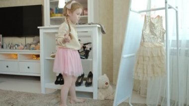 pigtails pembe bir etek ile neşeli küçük kız anne ayakkabı topuklu ve dansları anneler gardırop bir ayna önünde üzerinde çalışır