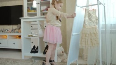 pigtails pembe bir etek ile neşeli küçük kız anne ayakkabı topuklu ve dansları anneler gardırop bir ayna önünde üzerinde çalışır