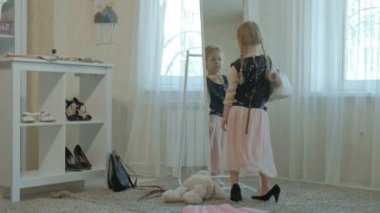 Yetişkin anneler elbise, elbise, topuklu ve dansları bir çanta, anneler gardırop bir ayna önünde neşeli kız pigtails pembe bir etek ile çalışır
