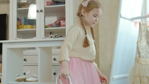 Веселая девушка с косичками примеряет одежду для взрослых матерей, платья, высокие каблуки, танцует перед зеркалом, мамин гардероб — стоковое видео