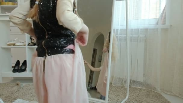 Fille gaie avec des queues de cochon dans une jupe rose essaie sur les vêtements des mères adultes, robes, talons hauts et danses devant un miroir avec un sac, garde-robe des mères — Video