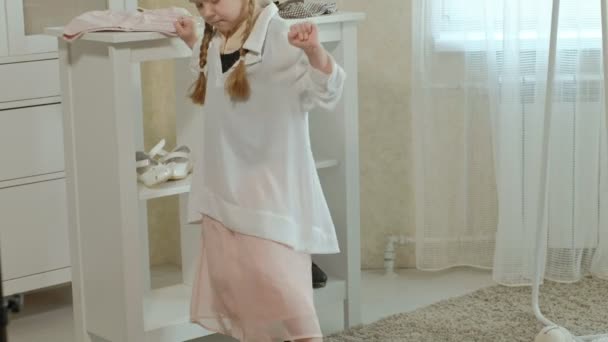 Veselá dívka s copánky v růžové sukni se snaží na dospělé matky oblečení, šaty, boty na podpatku a tance před zrcadlem s taškou, matky skříň — Stock video
