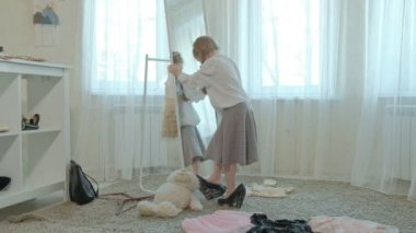 Yetişkin anneler elbise, elbise, topuklu ve dansları bir çanta, anneler gardırop bir ayna önünde neşeli kız pigtails pembe bir etek ile çalışır
