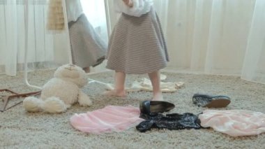 Yetişkin anneler elbise, elbise, topuklu ve dansları bir çanta, anneler dolap 4 k bir ayna önünde neşeli kız pigtails pembe bir etek ile çalışır