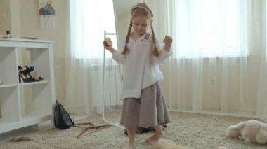 Yetişkin anneler elbise, elbise, topuklu ve dansları bir çanta, anneler gardırop bir ayna önünde neşeli kız pigtails pembe bir etek ile çalışır