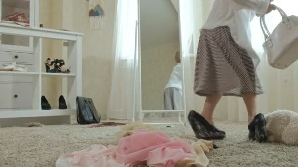 愉快的女孩与辫子在粉红色裙子的辫子尝试在成人母亲衣服、礼服、高跟鞋和跳舞在镜子前面与袋子, 母亲的衣柜 — 图库视频影像