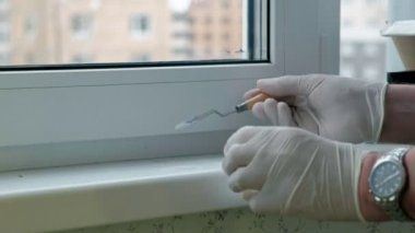 Lastik eldiven bir erkekte bir pencere pervazına geri yükler, Yapıştır hasarlı bölgeleri için bir spatula ile geçerlidir.