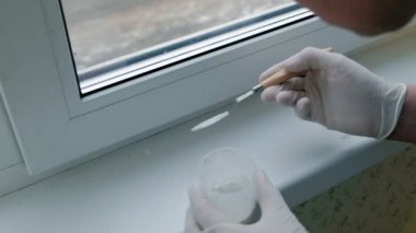 Lastik eldiven bir erkekte bir pencere pervazına geri yükler, Yapıştır hasarlı bölgeleri için bir spatula ile geçerlidir.