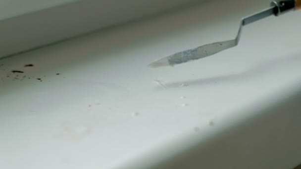 Ein Mann in Gummihandschuhen repariert ein Fensterbrett, trägt mit einem Spachtel Paste auf beschädigte Stellen auf — Stockvideo