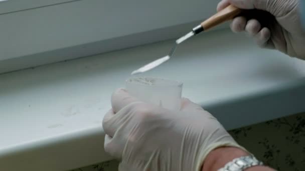 A man in rubber gloves restores a window sill, applies paste to damaged areas with a spatula — Stock Video