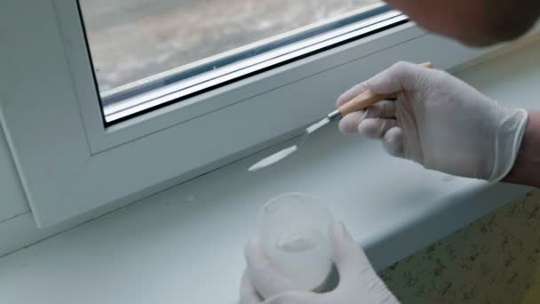 Un hombre con guantes de goma restaura un alféizar de la ventana, aplica pasta a las zonas dañadas con una espátula — Vídeos de Stock