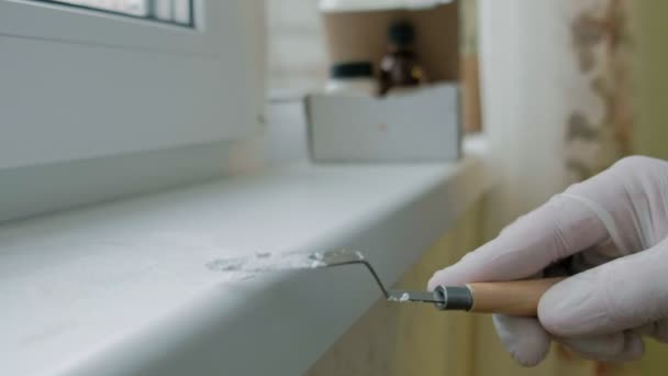 Ein Mann in Gummihandschuhen repariert ein Fensterbrett, trägt mit einem Spachtel Paste auf beschädigte Stellen auf — Stockvideo