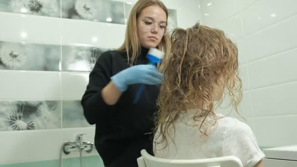 Kvinna Frisör kolorist hemma i badrummet sätter färg på håret på en ung kvinna, applicerar färgen med en borste på hår, skönhet, mode — Stockvideo