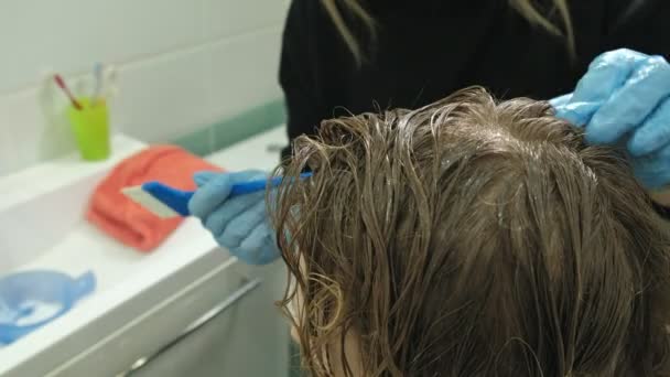 Mulher cabeleireiro colorista em casa no banheiro coloca tinta no cabelo de uma jovem, aplica tinta com uma escova no cabelo, beleza, moda — Vídeo de Stock