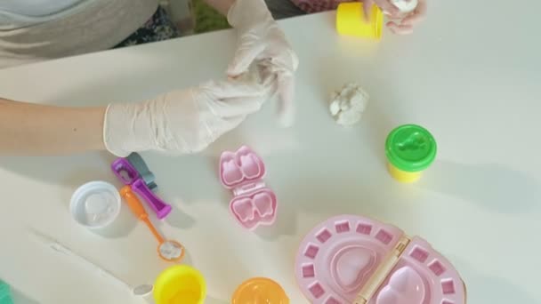 Молода жінка і дівчина формують зуби з пластиліну, грають у стоматолога, матері і дочки — стокове відео