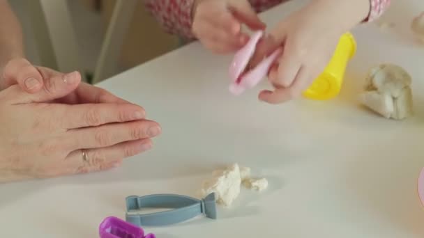 Joven mujer y niña moldean sus dientes de plastilina, jugar en el dentista, madre e hija, manos de cerca — Vídeos de Stock