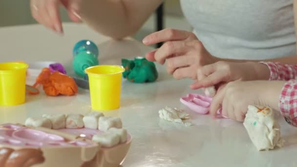 Uma jovem e uma menina moldam seus dentes de plasticina, inserir os dentes em uma mandíbula de brinquedo, jogar um dentista, mãe e filha — Vídeo de Stock