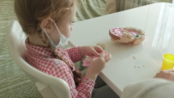 Uma jovem e uma menina moldam seus dentes de plasticina, inserir os dentes em uma mandíbula de brinquedo, jogar um dentista, mãe e filha — Vídeo de Stock