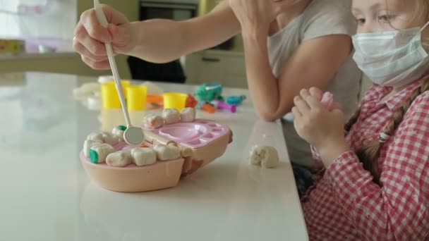 Une jeune femme et une fille moulent leurs dents à partir de la plasticine, insèrent leurs dents dans une mâchoire de jouet, font une inspection, jouent un dentiste, mère et fille — Video