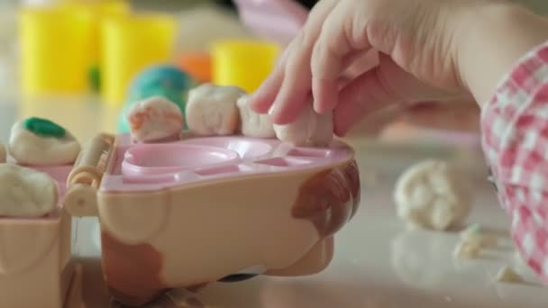 Una mujer joven y una niña moldean sus dientes de plastilina, insertan sus dientes en una mandíbula de juguete, hacen una inspección, juegan un dentista, madre e hija, primer plano de la mano — Vídeo de stock