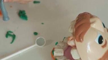 Genç bir kadın ve bir kız dişlerini gelen hamuru kalıp, dişlerini bir oyuncak çene içine yerleştirin, kaşlı ayraçlar ayarla, diş hekimi, anne ve kızı oynamak