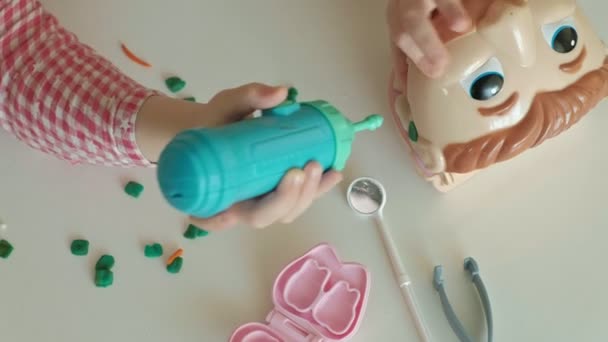 Uma jovem e uma menina moldam seus dentes de plasticina, inserir os dentes em uma mandíbula de brinquedo, remover aparelhos, jogar um dentista, mãe e filha , — Vídeo de Stock