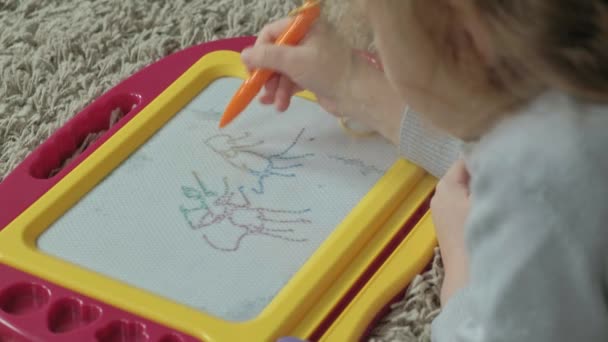 赤のウェーブのかかった髪を持つ小さな少女は床に位置し、マグネット ボードに描画します。教育過程の概念。クローズ アップ — ストック動画