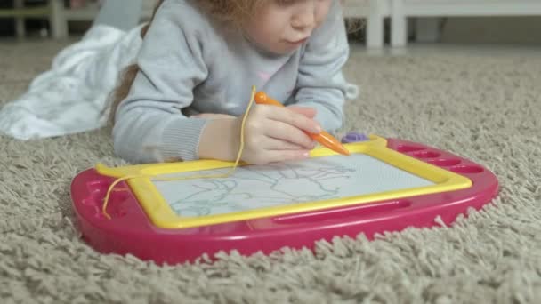 一个红色波浪形头发的小女孩躺在地板上 画在一面磁板上 教育过程的概念 特写4K — 图库视频影像