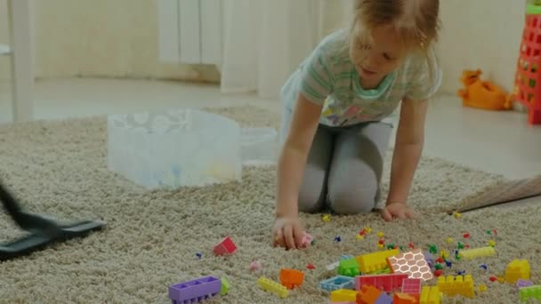 Mama i Córka, młoda kobieta sprząta odkurzaczem, mała dziewczynka z blond włosami zbiera zabawki, Projektant w pojemniku, Mama pomaga — Wideo stockowe