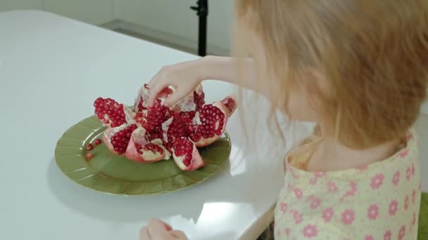 Gelukkig klein meisje met blond haar eet gezond voedsel concept, granaatappel, close-up portret — Stockvideo