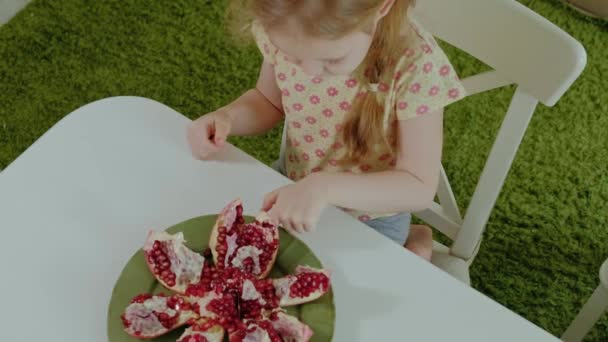 ブロンドの髪の幸せな女の子を食べるザクロ 健康食品のコンセプト ドリンクク ローズ アップ — ストック動画
