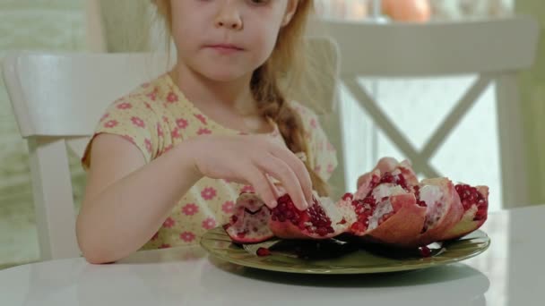 Счастливая маленькая девочка с светлыми волосами ест гранат, концепция здоровой пищи, портрет крупным планом — стоковое видео