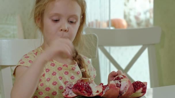 Niña feliz con el pelo rubio come granada, concepto de comida saludable, retrato de cerca — Vídeos de Stock